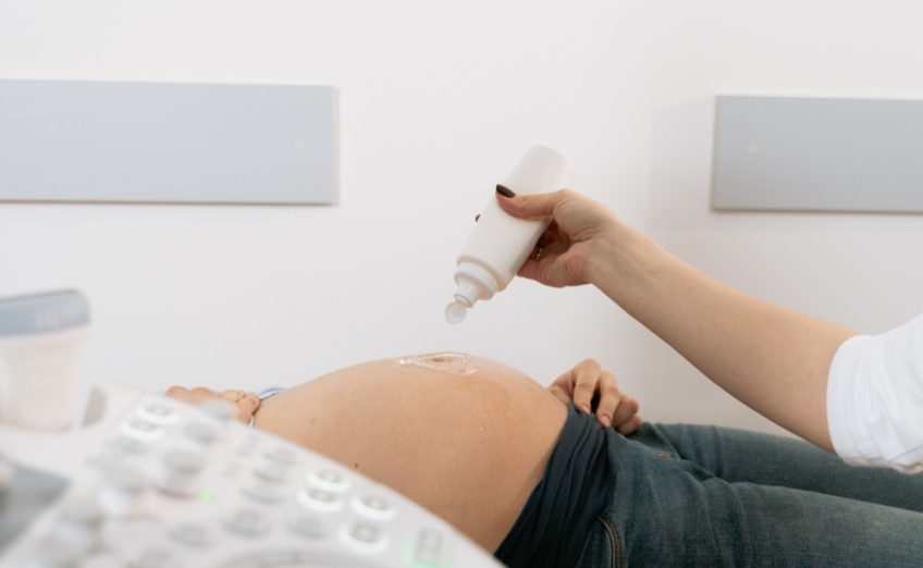 Bác sĩ dùng đầu dò siêu âm bụng cho mẹ bầu, cận cảnh không lộ mặt