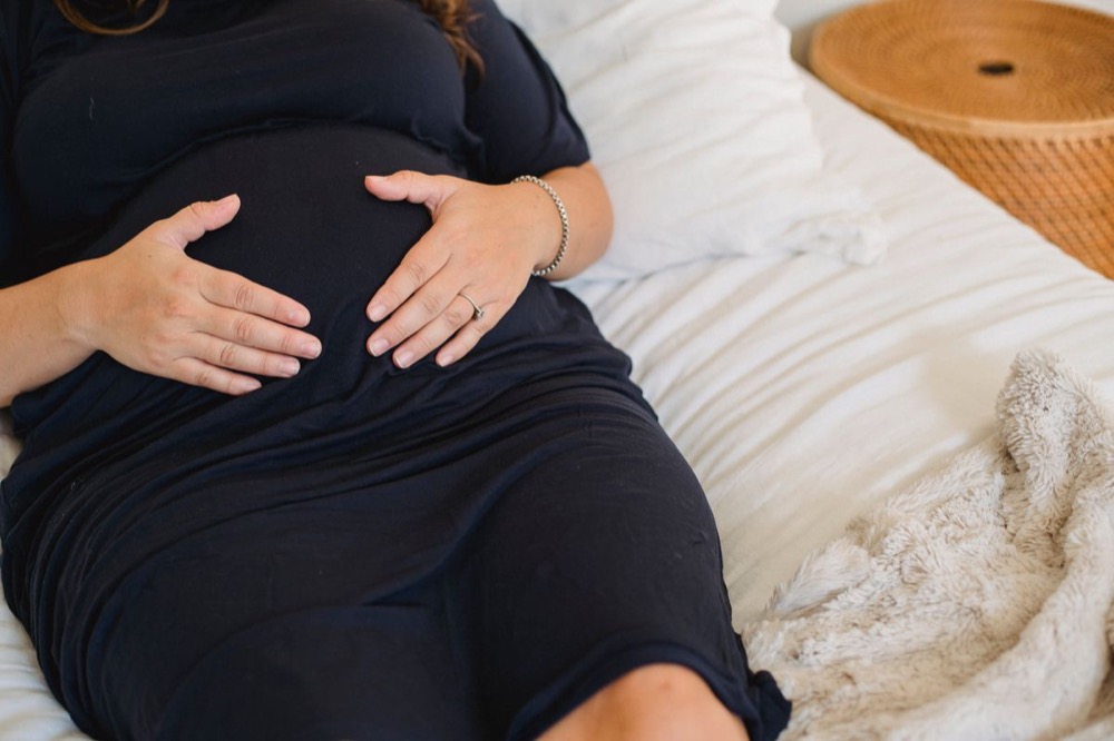 Mẹ bầu nằm nghỉ trên giường, tay đặt lên bụng